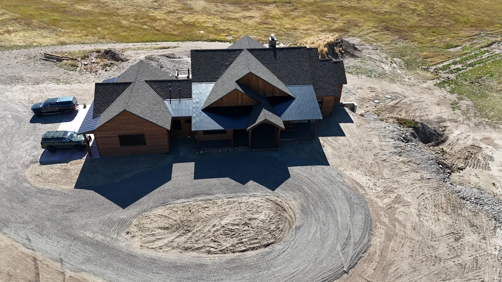 A drone view of a finished home at the end of a looping gravel drive
