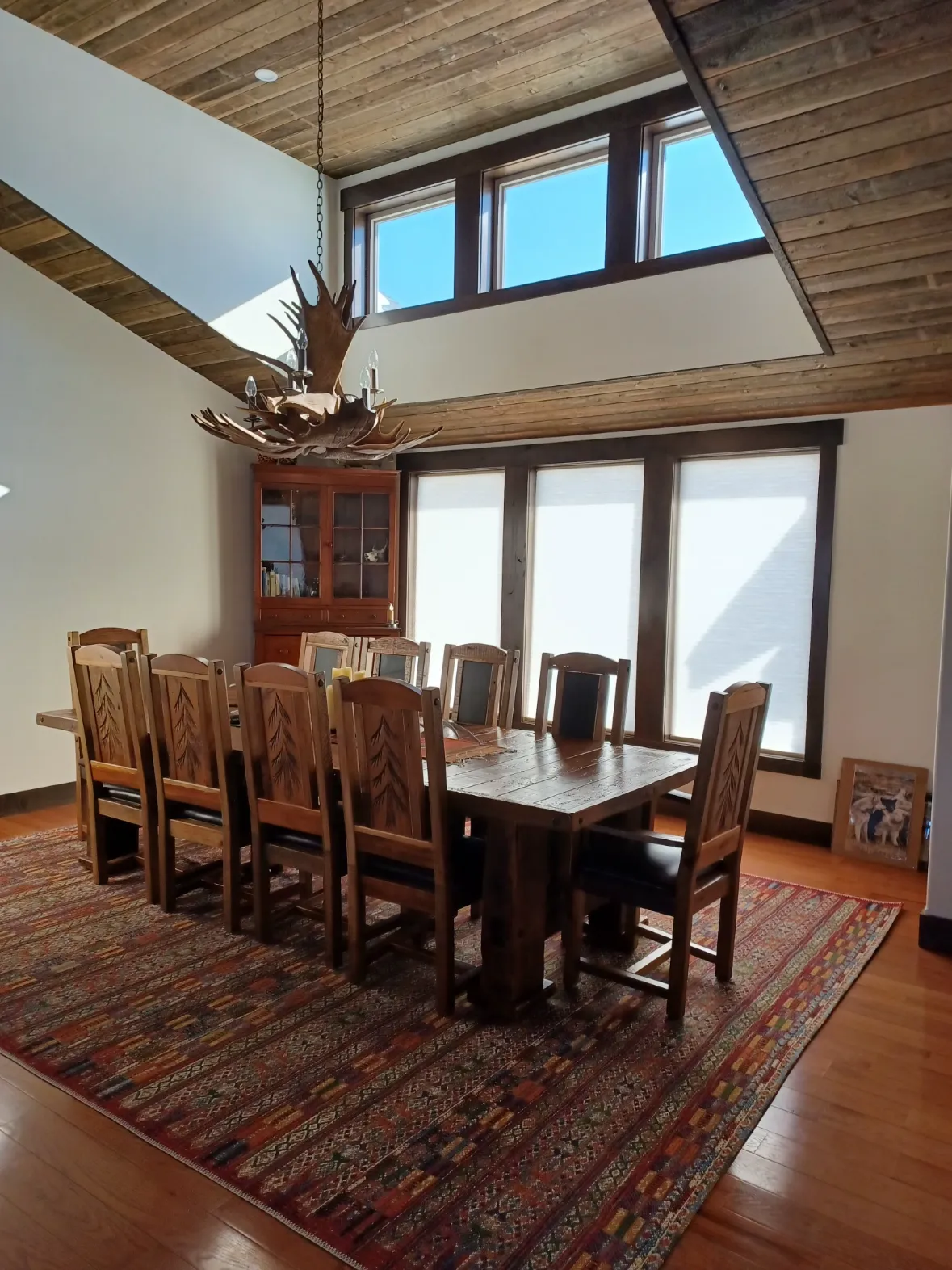 A dining room with a long wooden table under clerestory windows and a timber ceiling