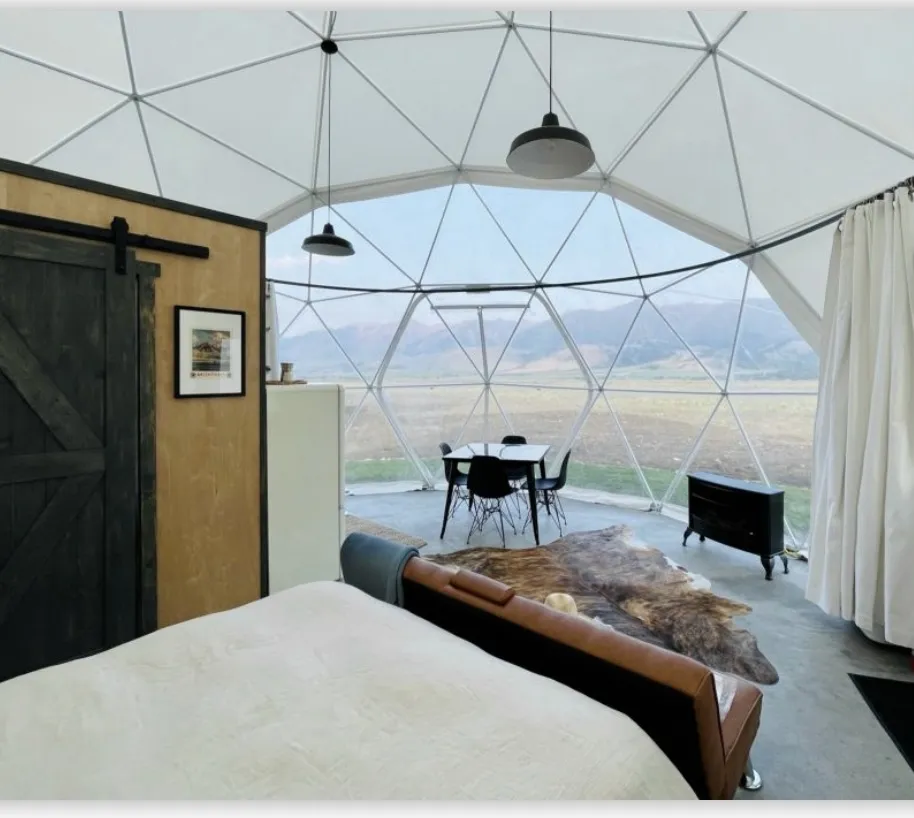 Inside a geodesic dome: a bed, a sliding barn door and a window-wall looking out over the valley