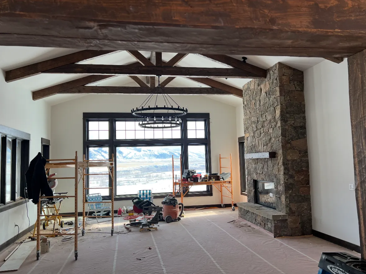 A great room mid-finish, a stone fireplace wall and tall windows under scissor trusses