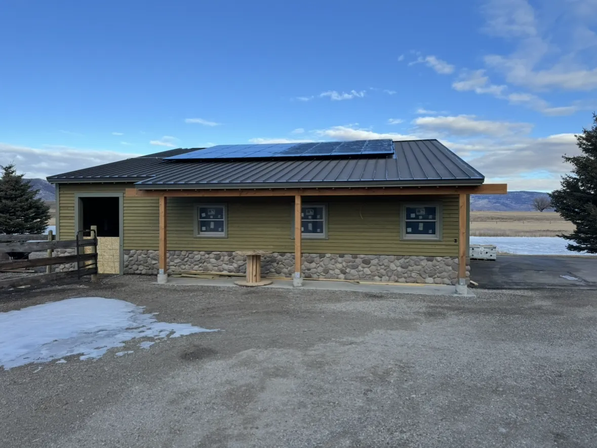 A single-storey home with a stone wainscot and solar panels on its metal roof