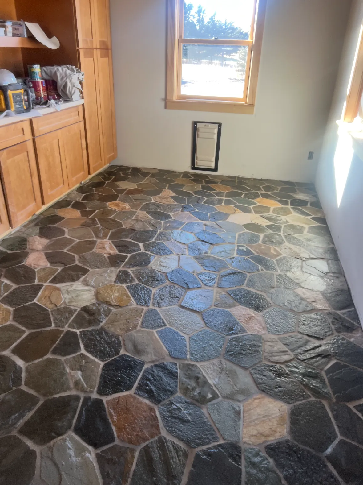 A room floored in large irregular slate pieces, cabinetry along one wall