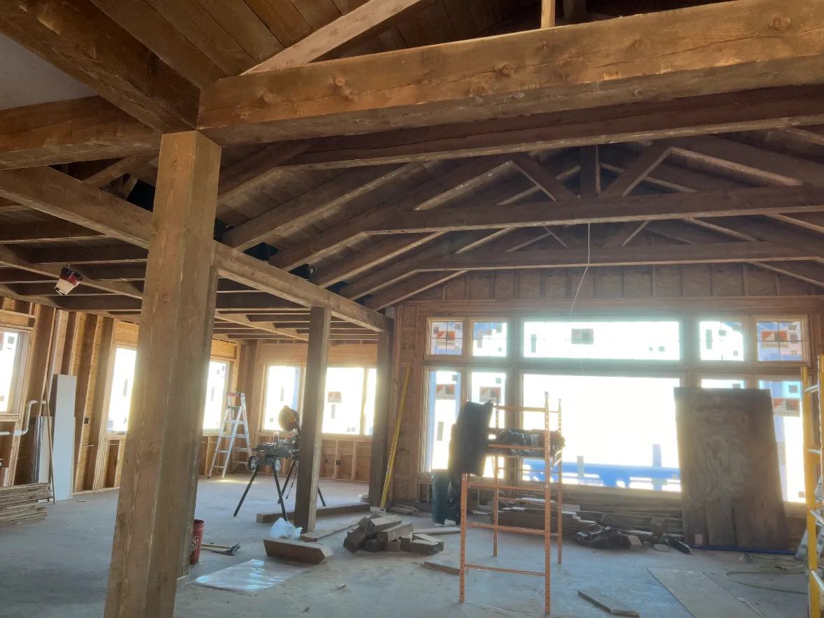 Heavy timber posts and beams standing in an open interior before the finishes go in